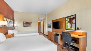 A hotel room with a large bed, a desk with a chair, a television, and artwork on the walls.