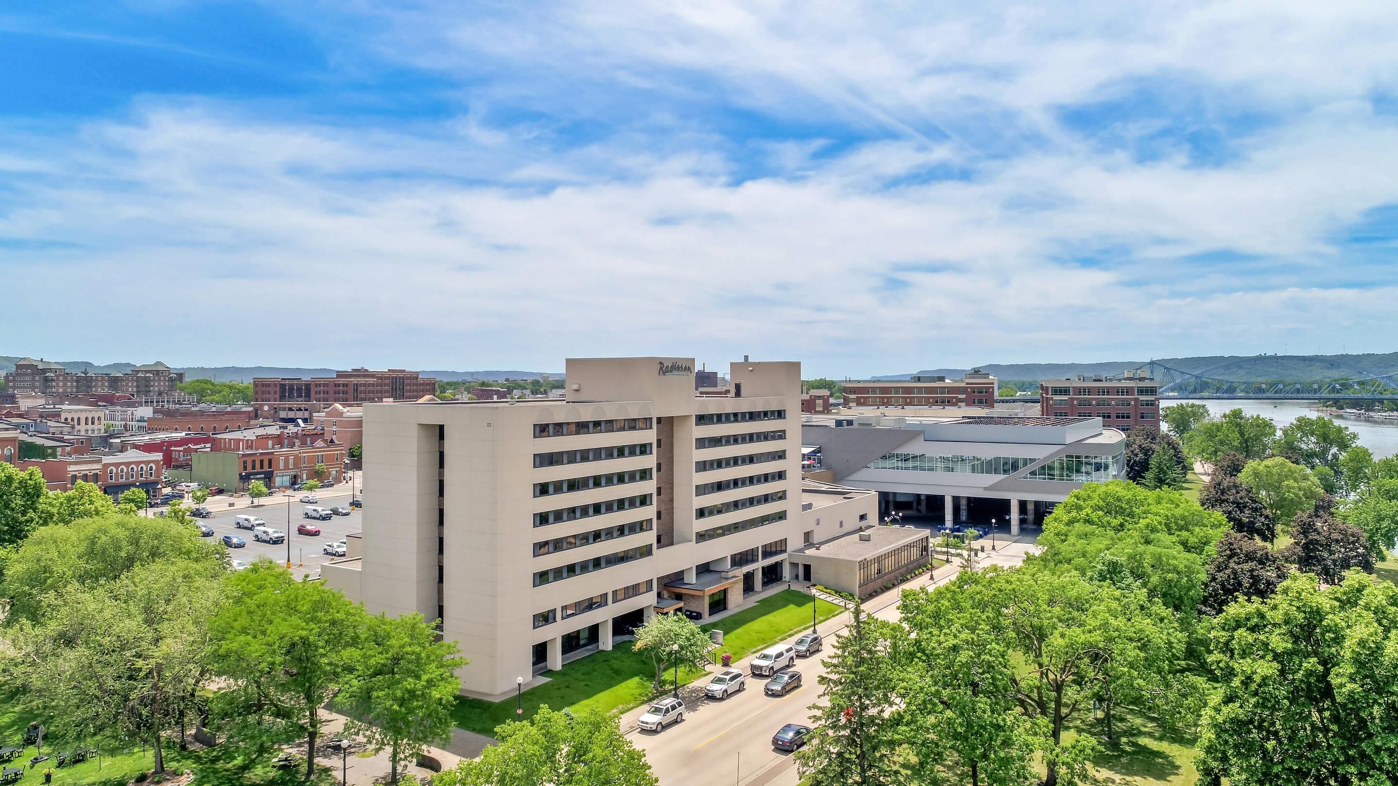 A modern building with multiple floors, a parking lot, and a river in the background.