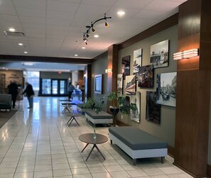 Un hall d’hôtel comprenant un comptoir d’accueil, un espace salon et des œuvres d’art accrochées aux murs.