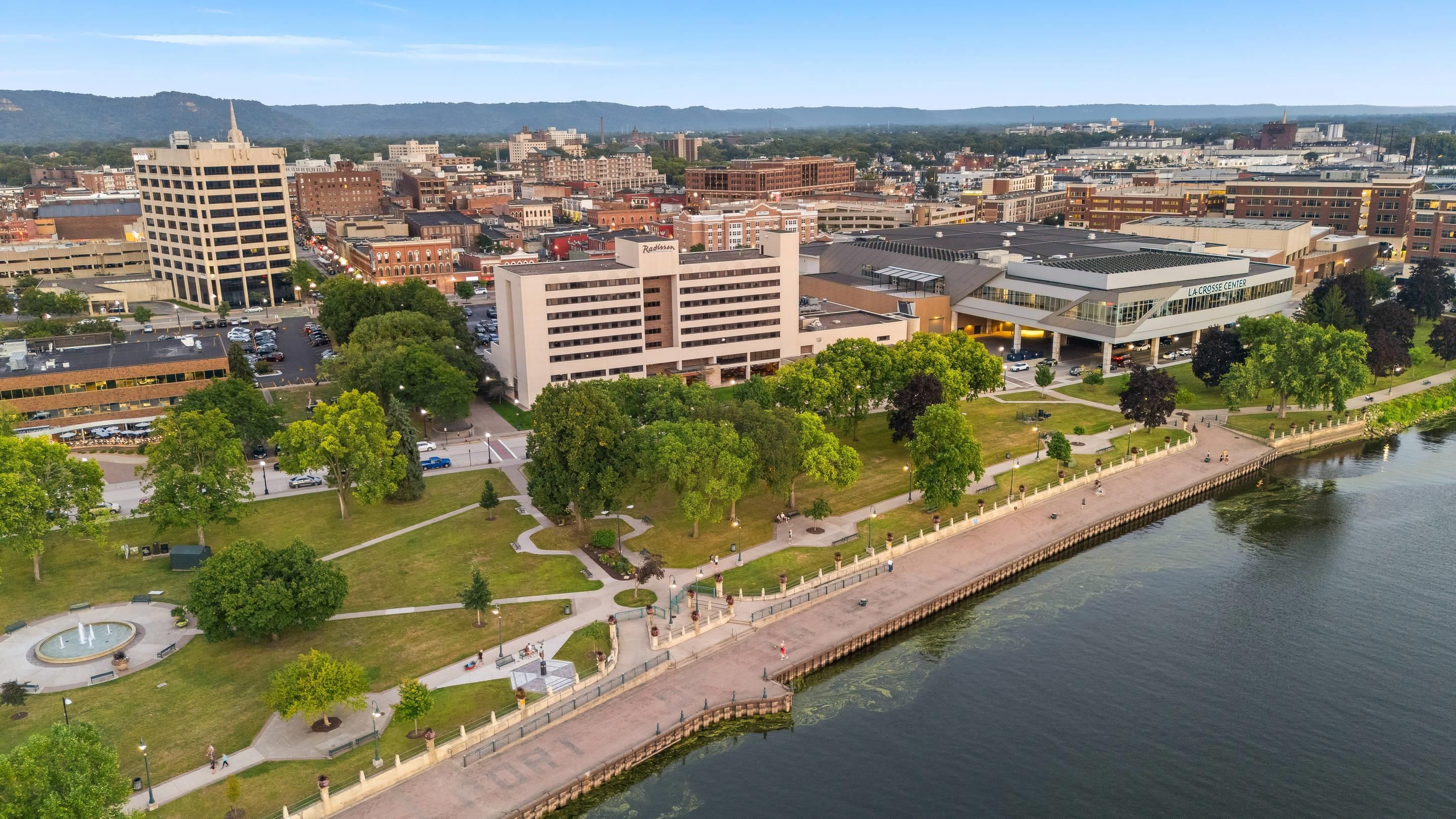 Eine Stadtansicht mit einem Fluss, einem Park mit einem Brunnen und einem modernen Gebäude mit der Aufschrift 'LA CROUSE CENTER'.