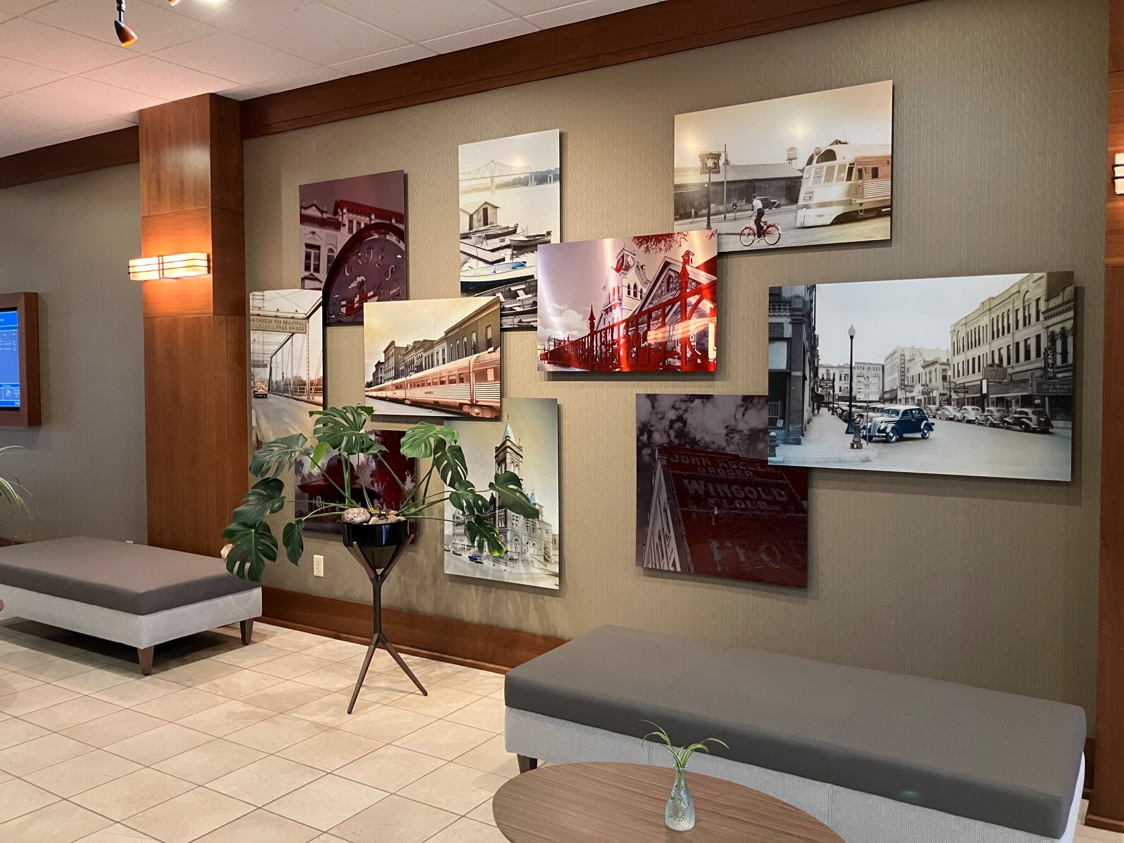 Un hall d’entrée avec un espace salon, un mur décoré de diverses photographies et une plante au centre.