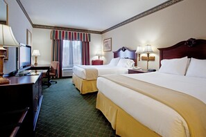 A hotel room with two beds, a desk with a television, and a chair.