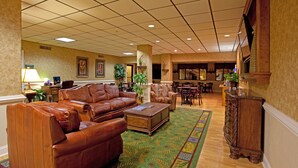 Eine großzügige Lobby mit Ledersofas, einem Couchtisch und einem gemusterten Teppich.