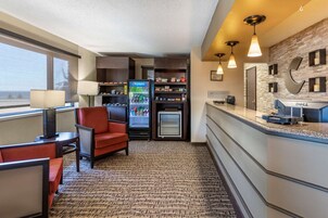 Habitación de hotel con kitchenette, refrigerador, microondas, escritorio, silla y un amplio ventanal.