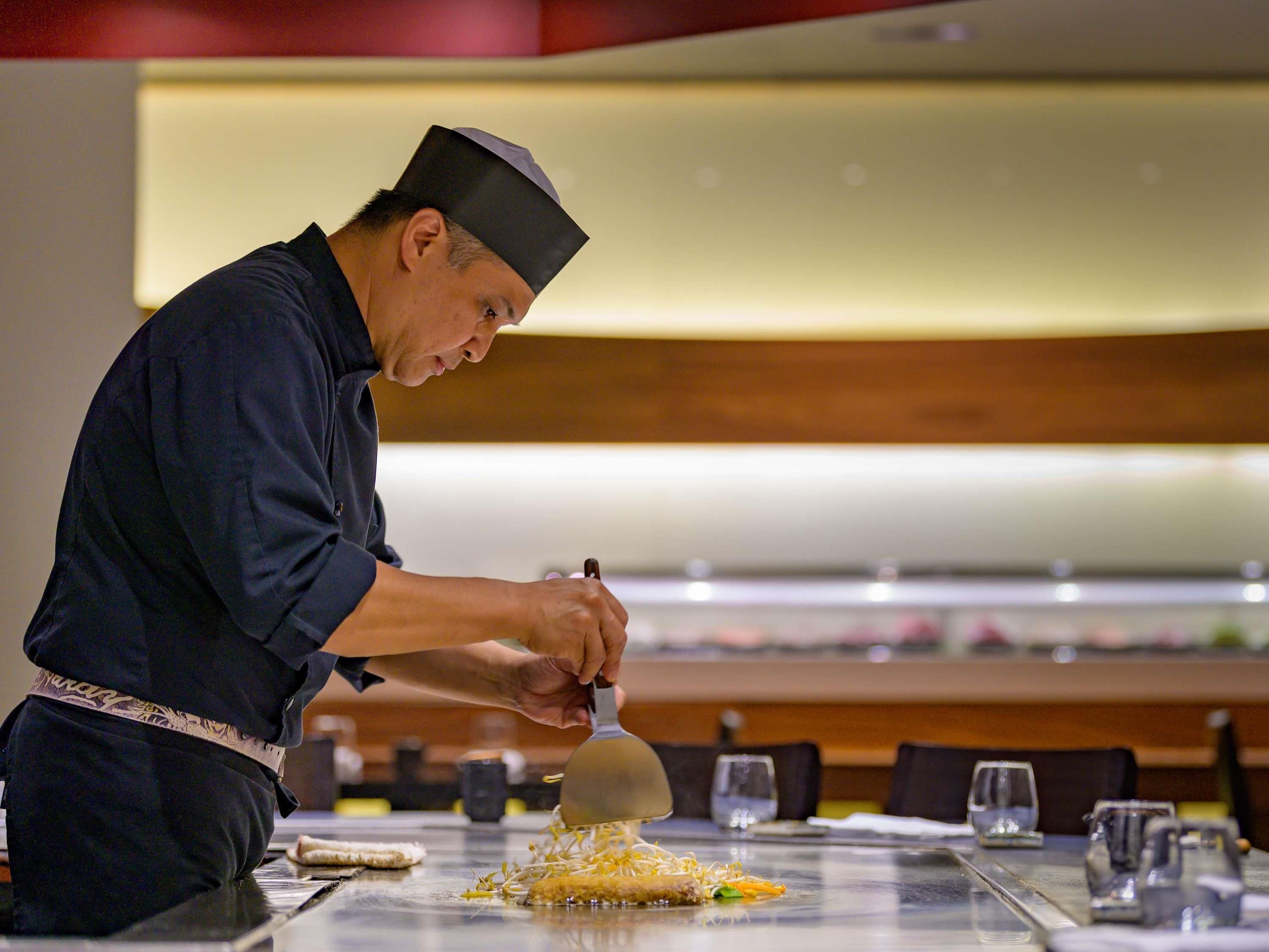 A chef preparing food at a table in a restaurant.