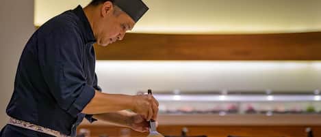 A chef preparing food at a table in a restaurant.