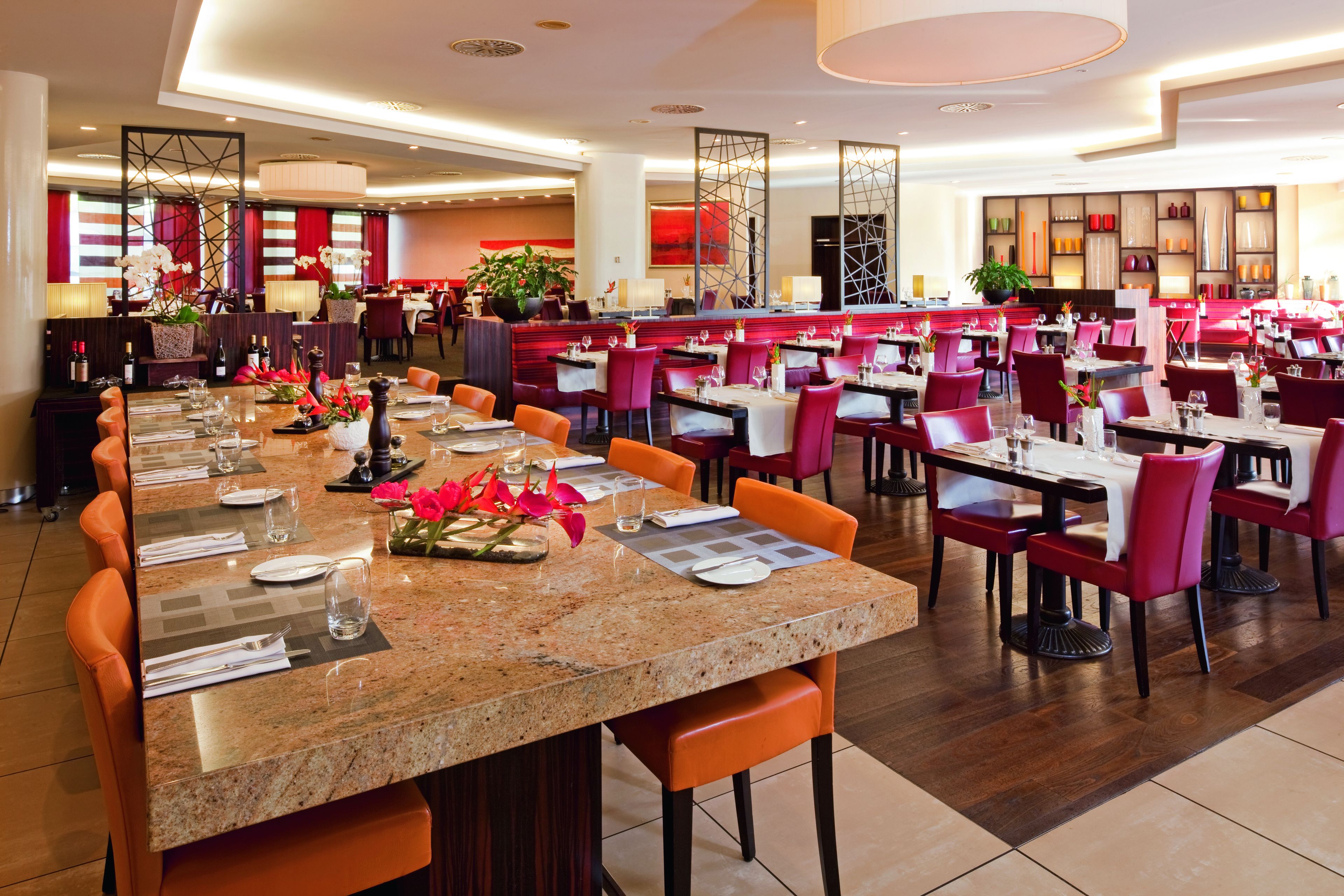 A spacious restaurant with multiple dining tables and chairs, a long counter, and a bar area.