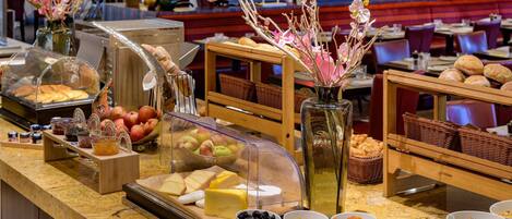 Un bufé con diversos alimentos, entre ellos frutas, quesos y frutos secos.