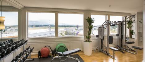 A gym with a view of an airport, exercise equipment, and a large window.
