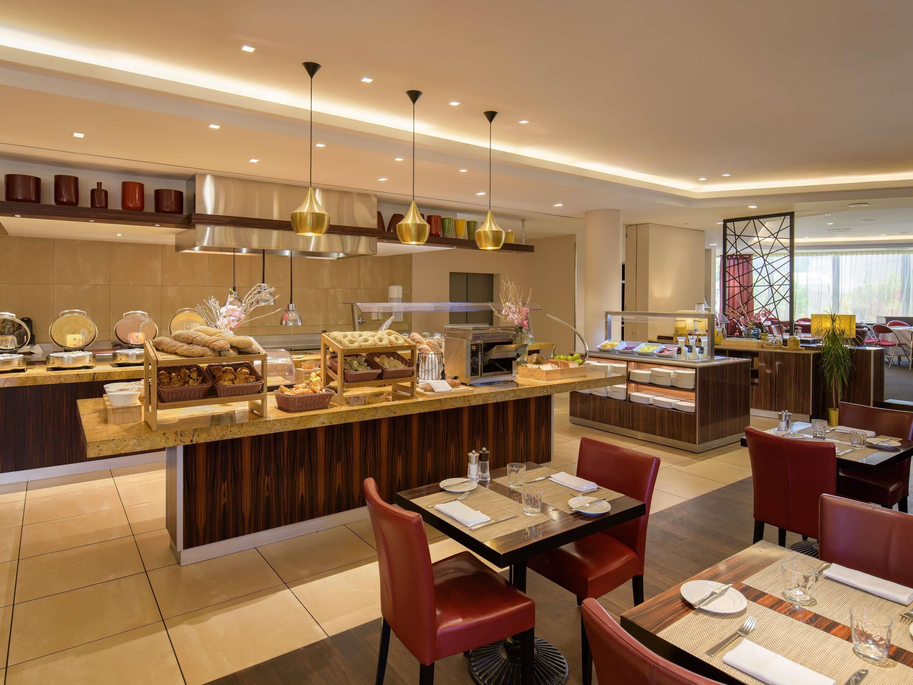 A modern hotel dining area with a central island, multiple seating options, and a buffet setup.