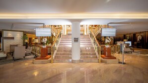 En rummelig lobby med en imponerende trappe, behagelige siddepladser og en reception.