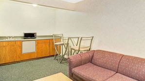 A compact kitchen with a microwave, a small refrigerator, and two chairs.
