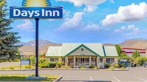 A Days Inn with a green roof and a sign with a sunburst design.