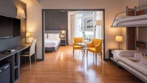 A modern hotel room with a bed, a desk, a chair, a sofa, and a TV. - Hotel Madrid Plaza de España Affiliated by Meliá (Madrid)