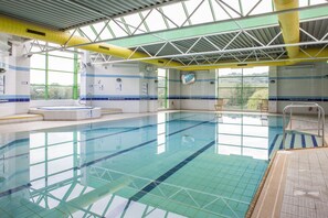 An indoor swimming pool with clear water, tiled walls, and a view of greenery outside. - Holiday Inn Stoke on Trent M6, Jct 15 by IHG (Newcastle-Under-Lyme)