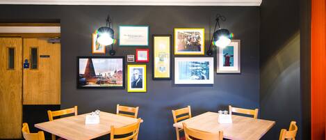 A dining area with wooden tables and chairs, framed pictures on the wall, and a sign indicating the staff room.