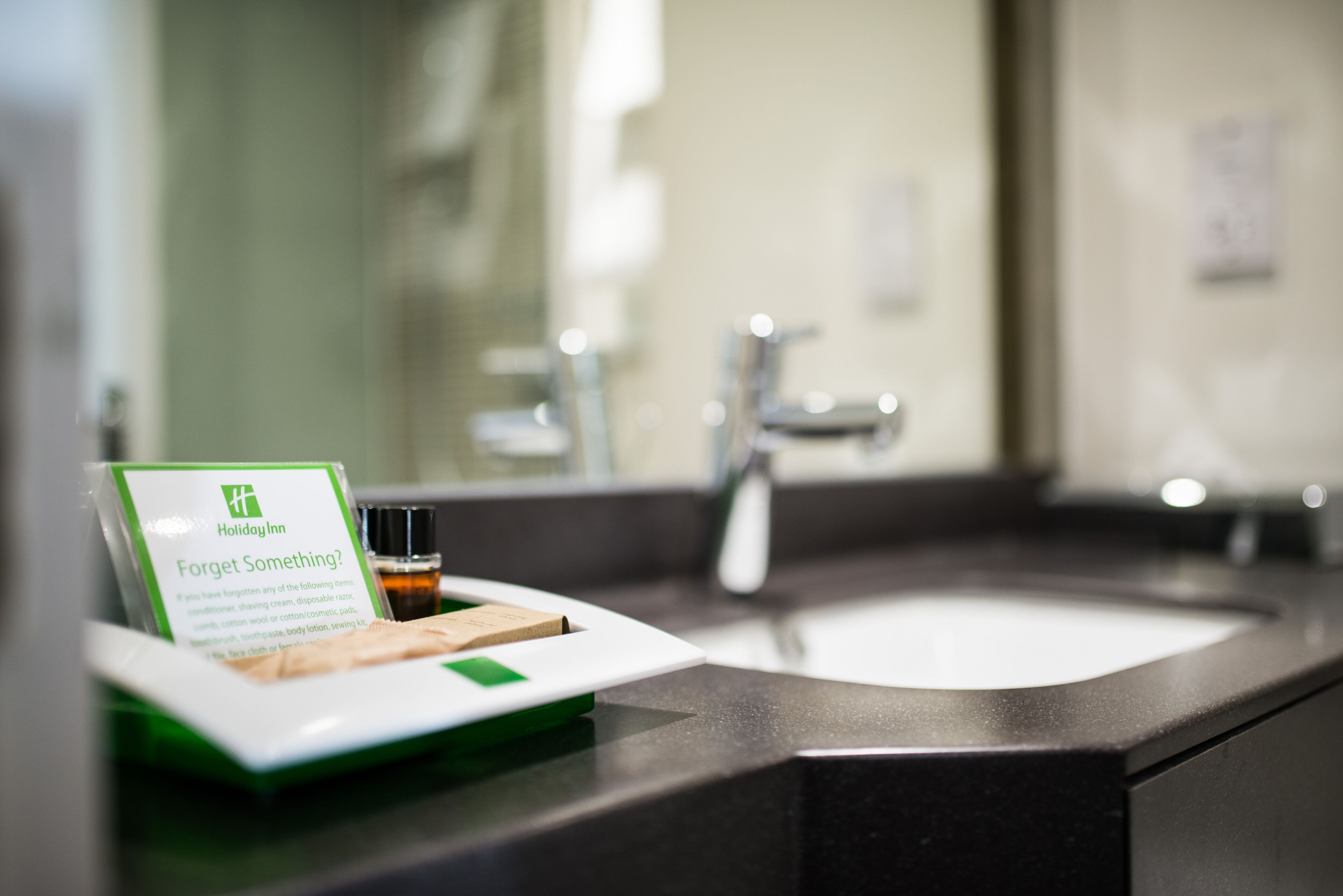 Ein Badezimmer-Waschtisch mit Waschbecken, Spiegel und einer Aufstellung von Toilettenartikeln.