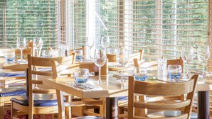 A restaurant with wooden tables and chairs, arranged for dining. - Holiday Inn Stoke on Trent M6, Jct 15 by IHG (Newcastle-Under-Lyme)