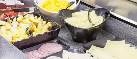 A buffet with various food items including fruits, cheeses, and meats.
