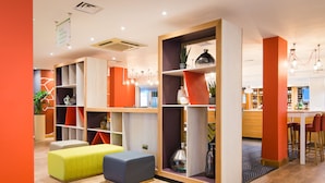 A modern interior with a seating area, wooden shelves, and a bar area. - Holiday Inn Stoke on Trent M6, Jct 15 by IHG (Newcastle-Under-Lyme)