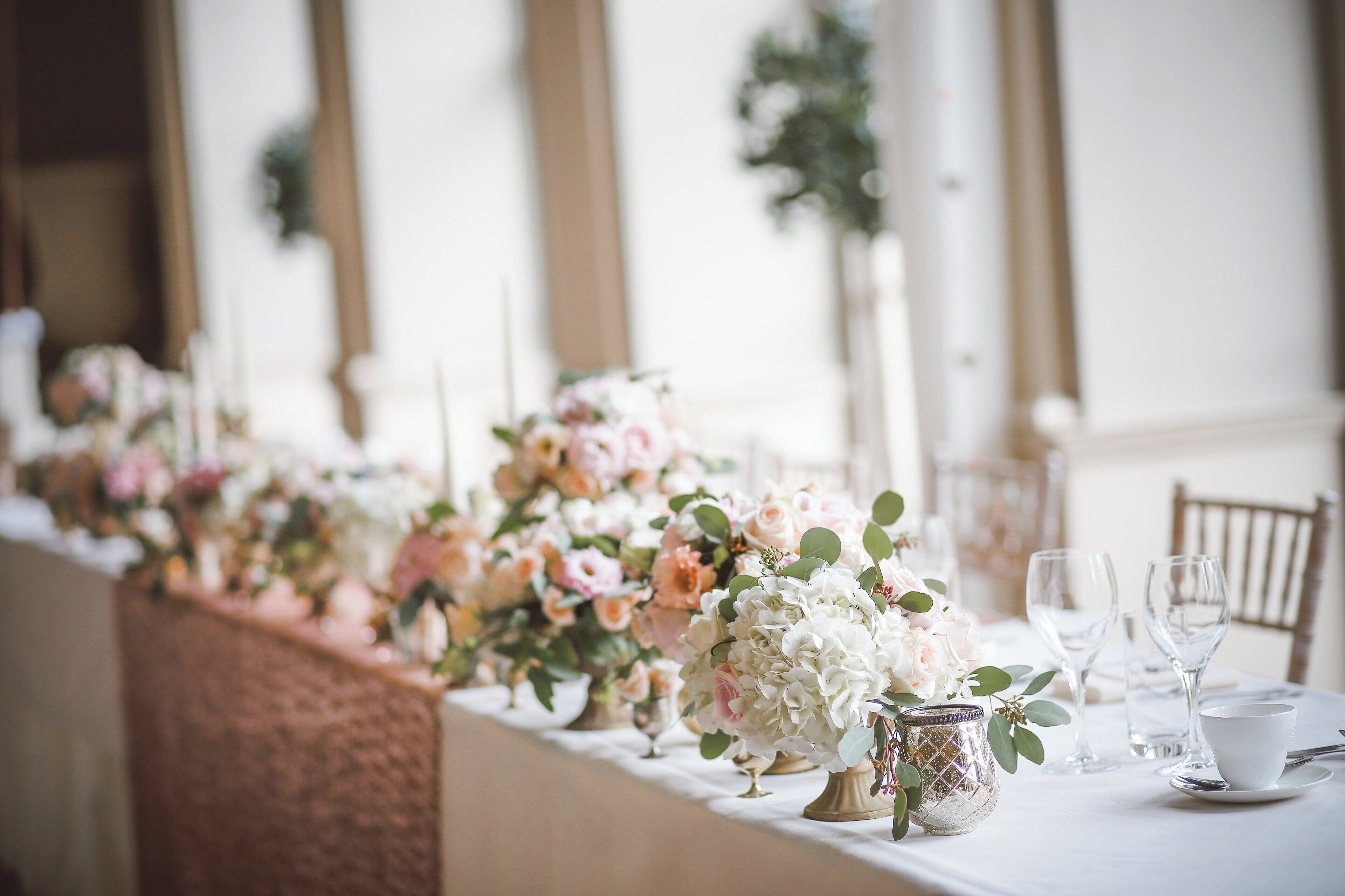 A long table with floral centerpieces, clear glassware, and a white tablecloth.