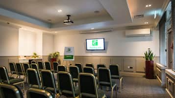 Ett konferensrum med rader av stolar, en projektorduk och en skylt med texten Holiday Inn.