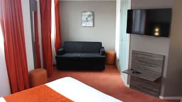 A hotel room with a bed, a sofa, a TV, and a small table.