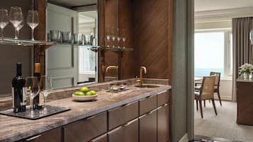 A modern kitchen with a marble countertop, wine glasses, and a bowl of limes.
