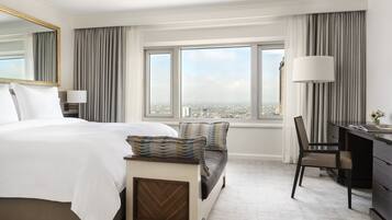 Una habitación de hotel con una cama grande, un escritorio y vistas a la ciudad a través de amplias ventanas.