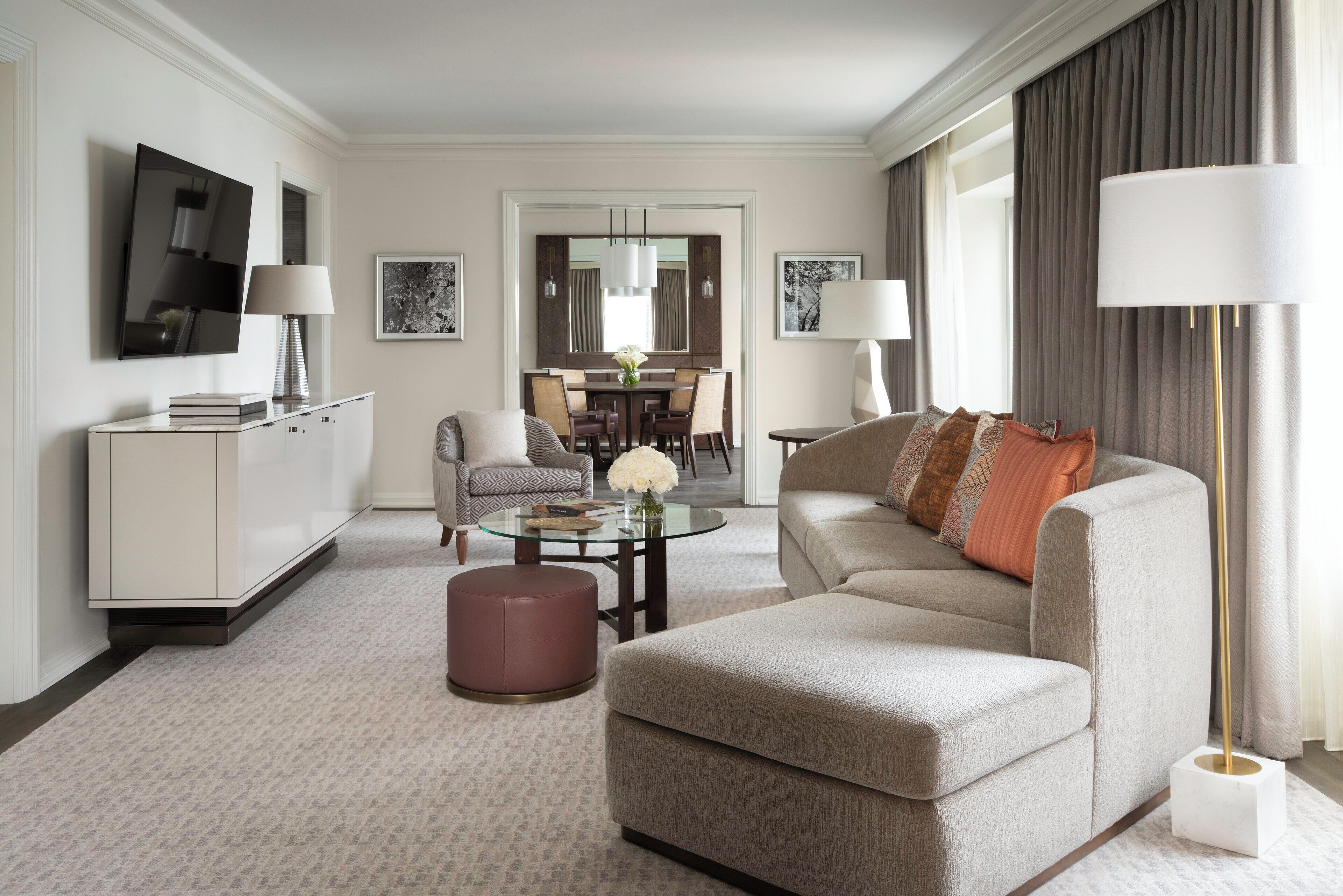 Quarto de hotel moderno com área de estar, mesa de jantar e sofá.