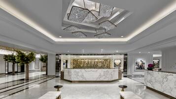 Un hall amplio con una recepción de mármol, candelabros modernos y un diseño limpio y elegante.