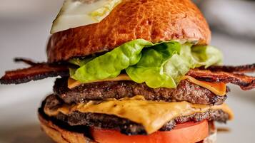 A close-up of a burger with lettuce, tomato, cheese, and bacon.