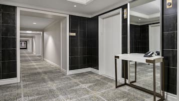 A hallway with black and white patterned carpet, a white reception desk, and a mirror.