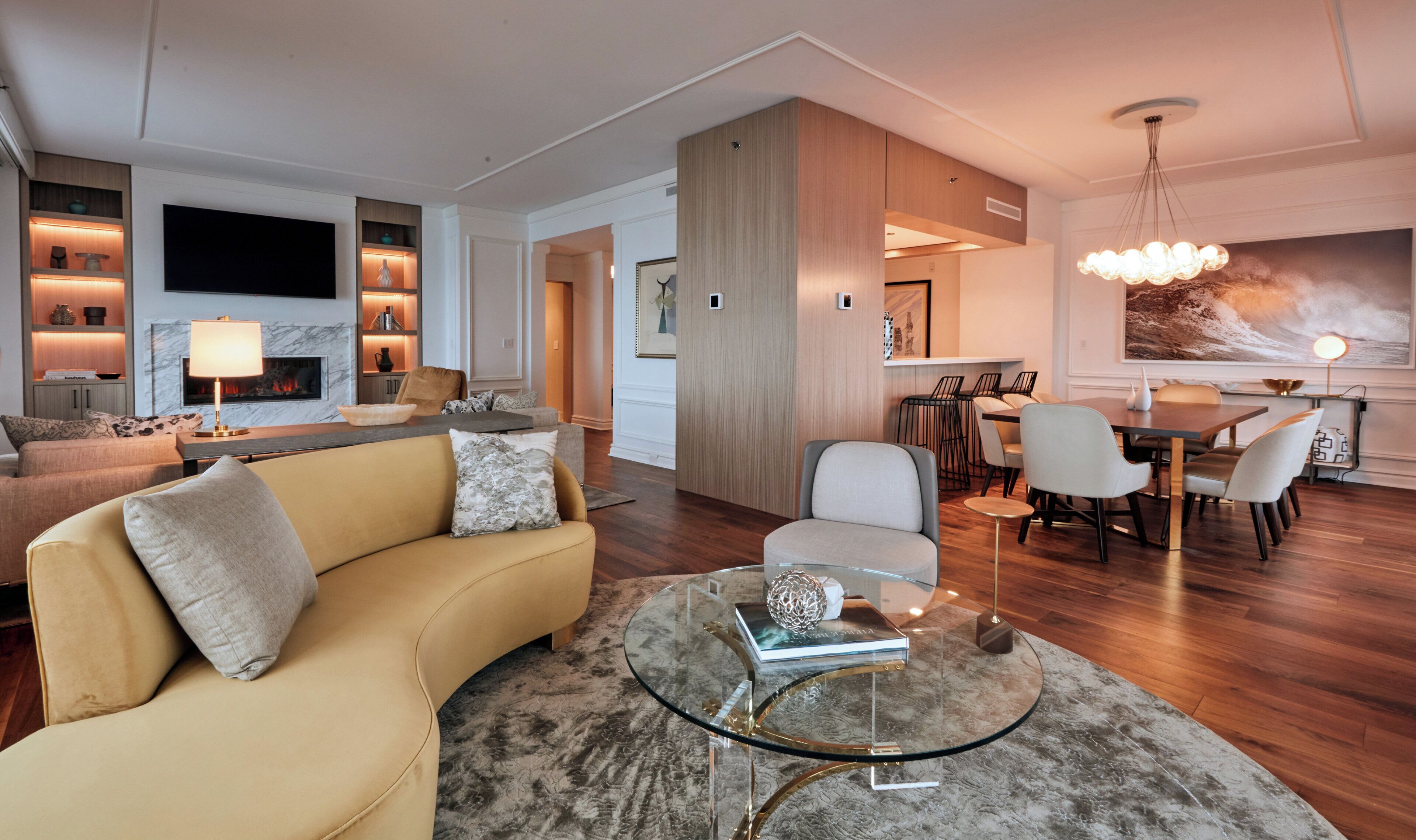 A modern living room with a sofa, a glass coffee table, and a dining area with chairs and a table.