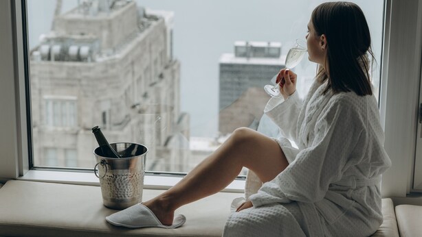 A person sitting by a window with a view of a cityscape, including a tall tower. - Four Seasons Hotel Chicago (Chicago)