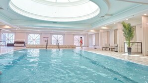 An indoor swimming pool with a skylight, a lifeguard chair, and a potted plant. - Four Seasons Hotel Chicago (Chicago)
