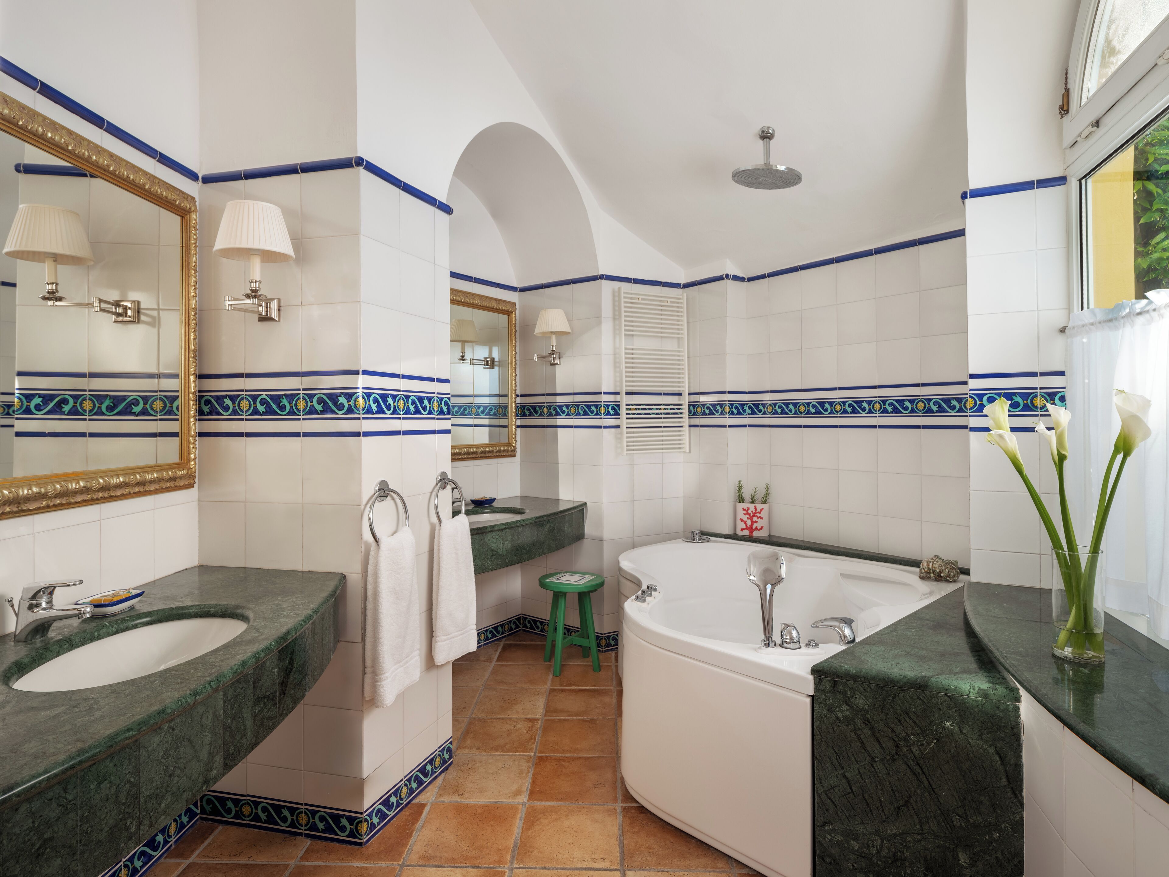 A bathroom with two sinks, a bathtub, and a green stool.
