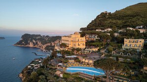 Una villa costera con piscina, jardines en terrazas y vistas al mar.