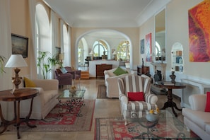 A spacious living room with a fireplace, multiple seating areas, and large windows.