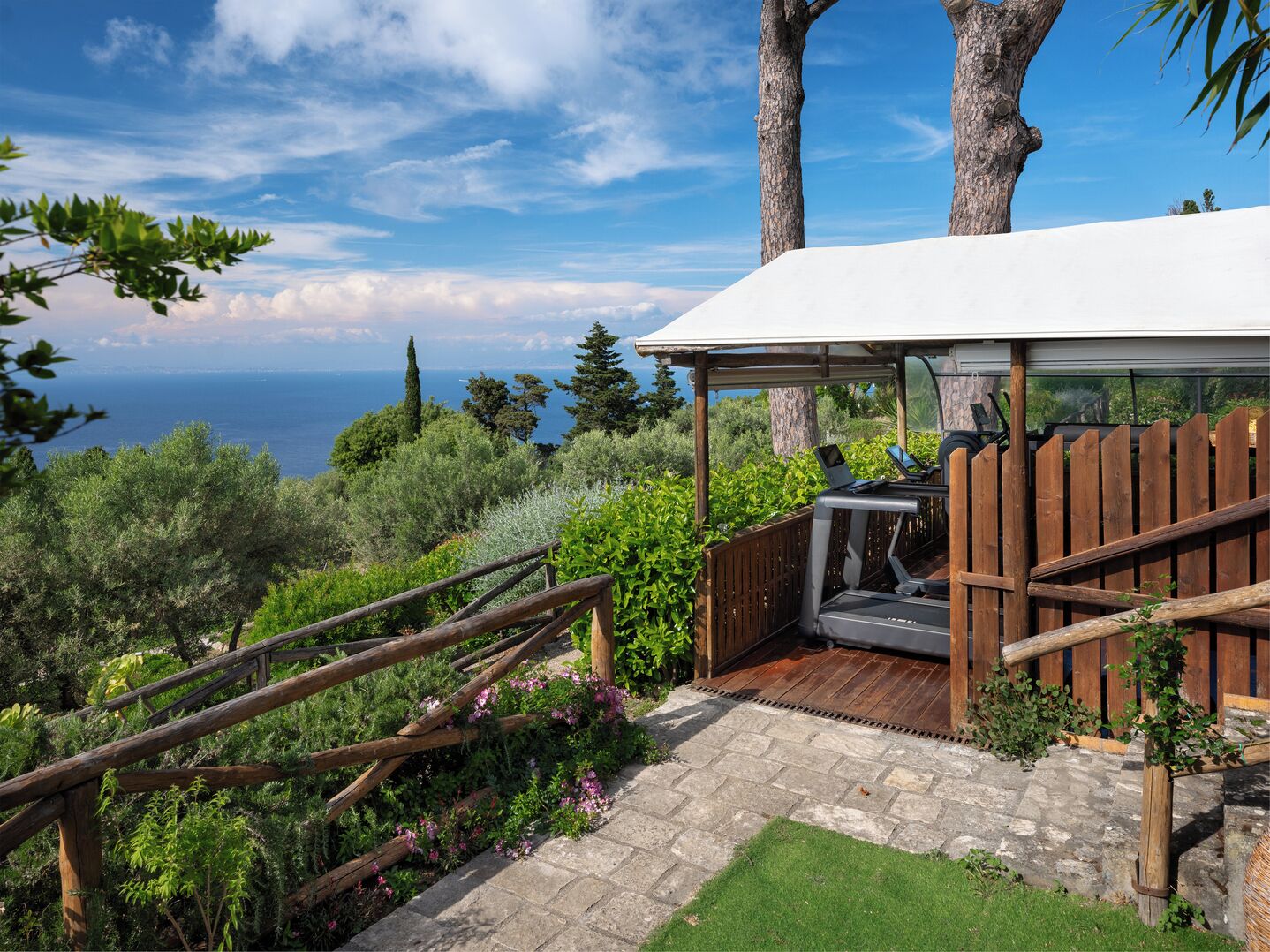 A covered outdoor area with a wooden deck, a pergola, and a view of the sea.