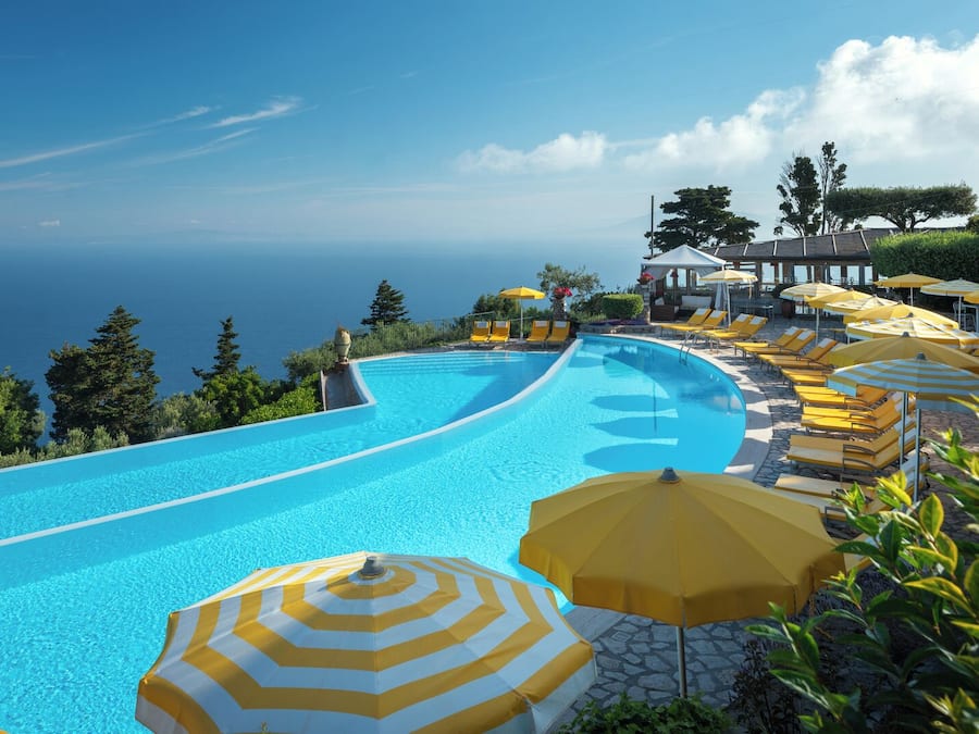 Una piscina al aire libre, sombrillas, sillones reclinables de piscina