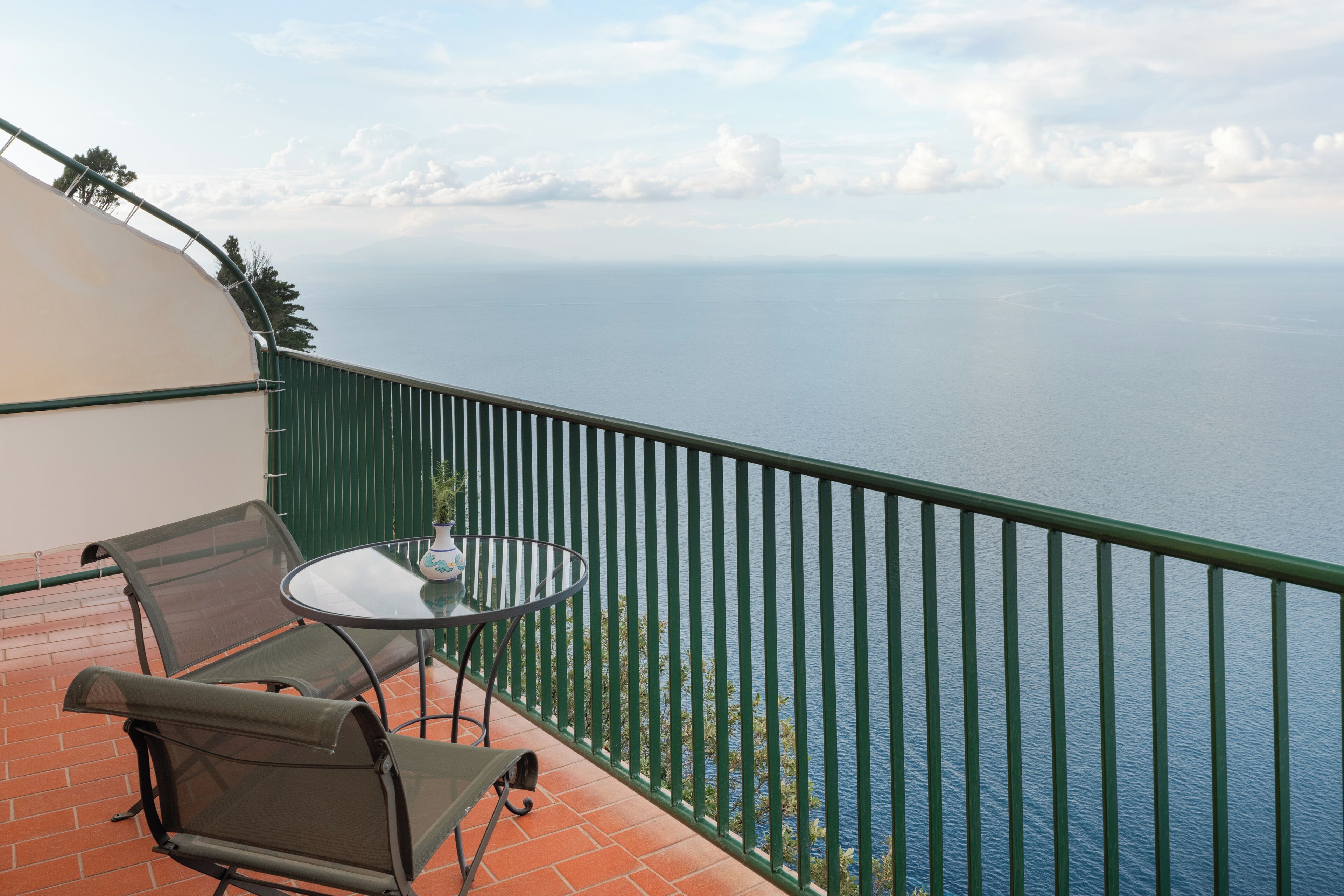 A balcony with a table and chairs, overlooking a body of water.