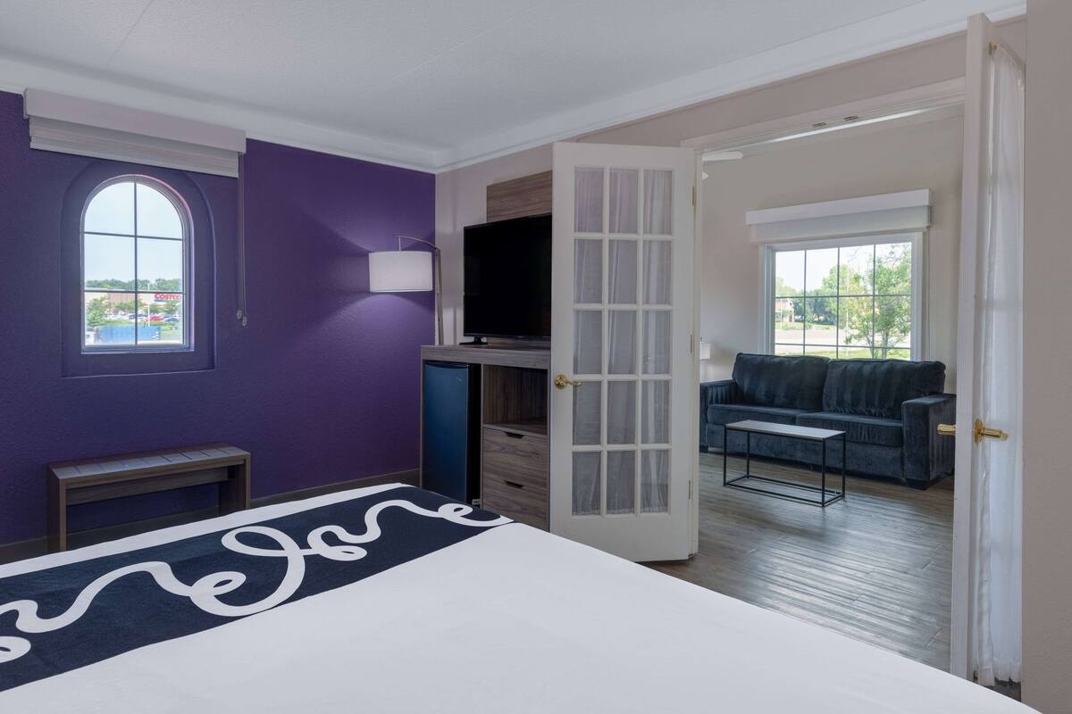 A hotel room with a bed, a TV, a desk, and a sofa.