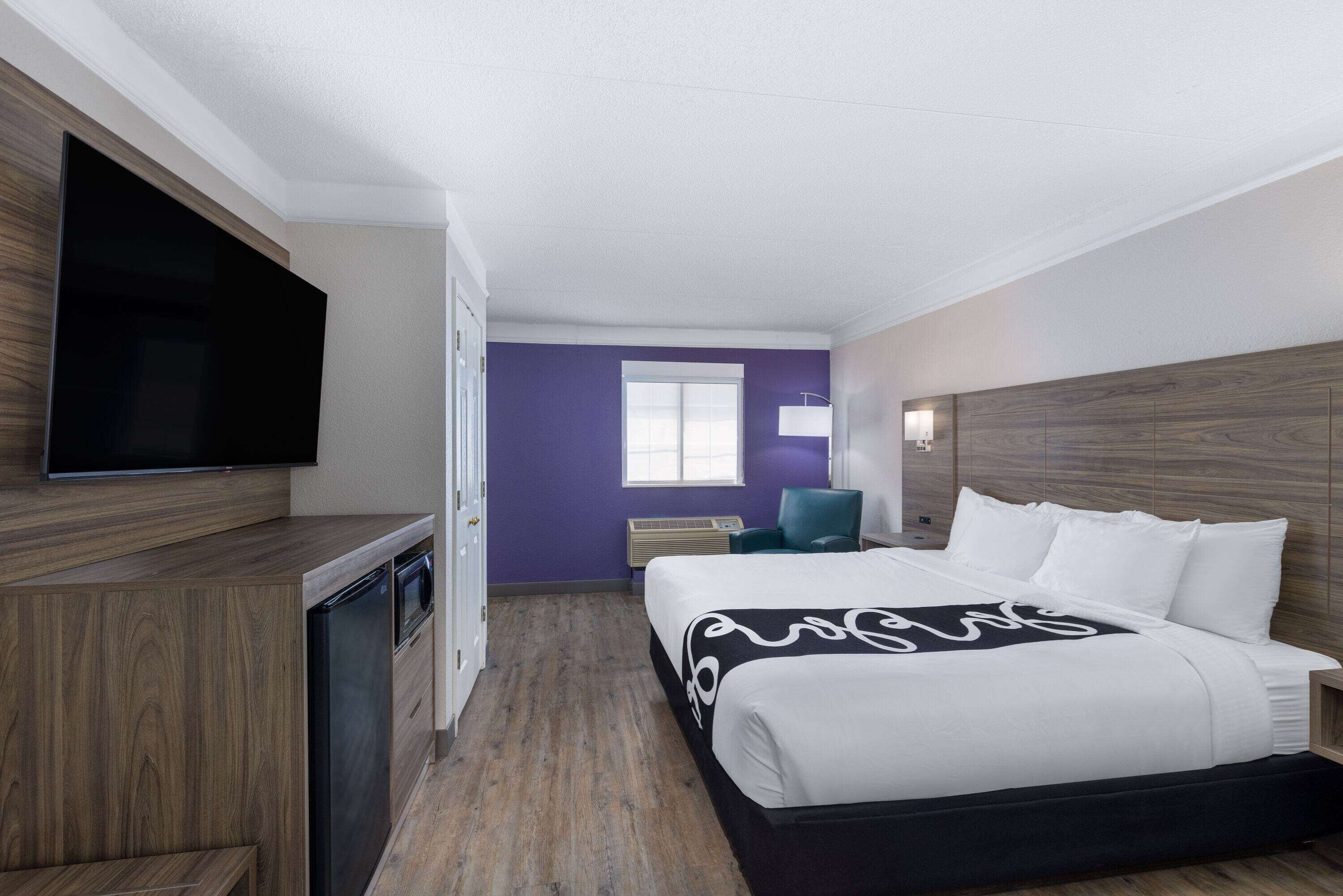 A hotel room with a bed, a flat-screen TV, a desk, and a chair.