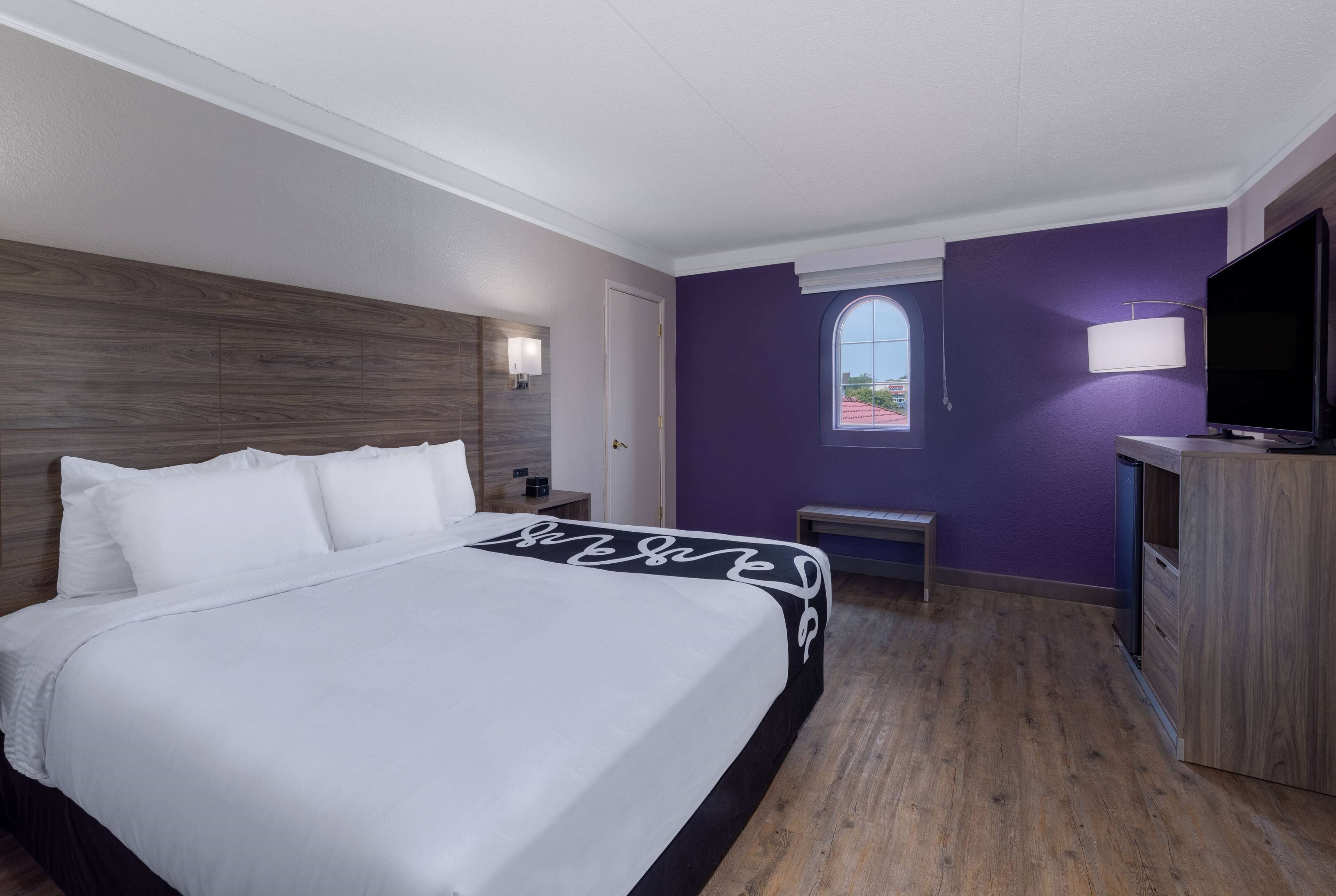 Une chambre d’hôtel avec un grand lit, une télévision, un bureau et une fenêtre donnant sur un beau paysage.