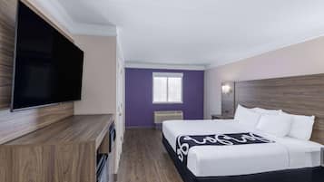 Habitación de hotel con cama, televisión de pantalla plana, ventana y cabecero de madera.