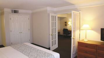 Quarto de hotel com cama, escrivaninha, cadeira, cômoda e televisão.