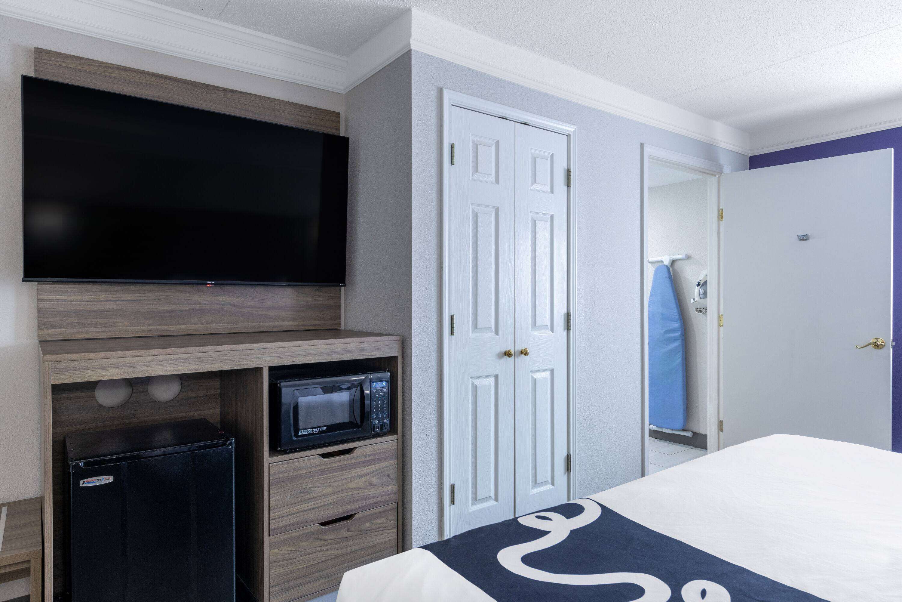 Ein Hotelzimmer mit Bett, Fernseher, Mikrowelle und Kleiderschrank.