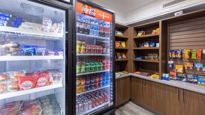 Máquina expendedora llena de aperitivos y bebidas, incluyendo un refrigerador de Coca-Cola.