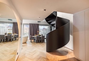 A modern interior with a spiral staircase, a dining area with chairs and a table, and large windows.